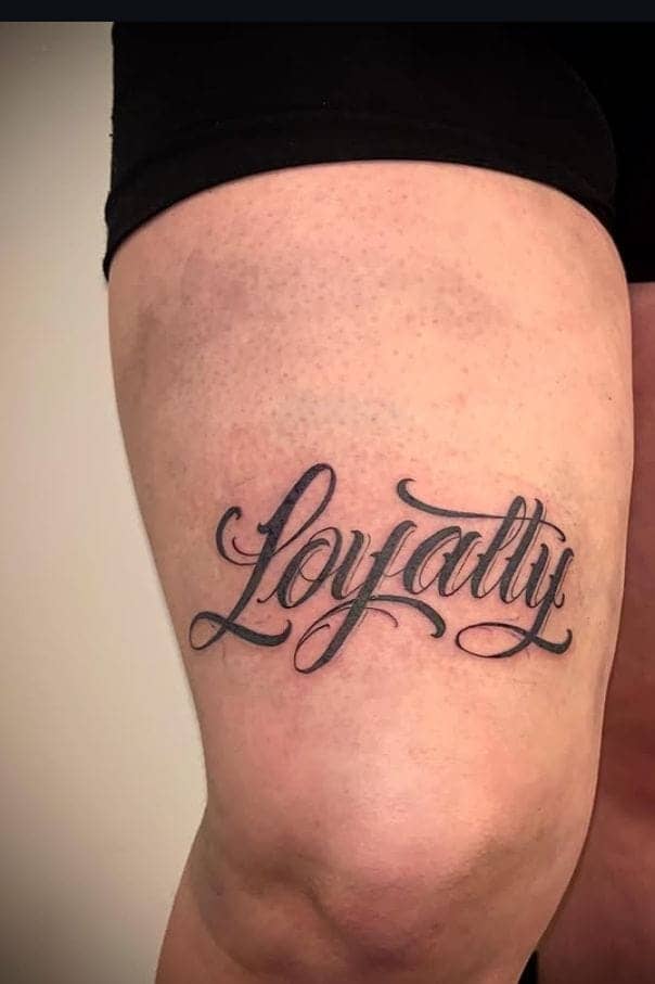 Elegant Script Loyalty Thigh Tattoo 